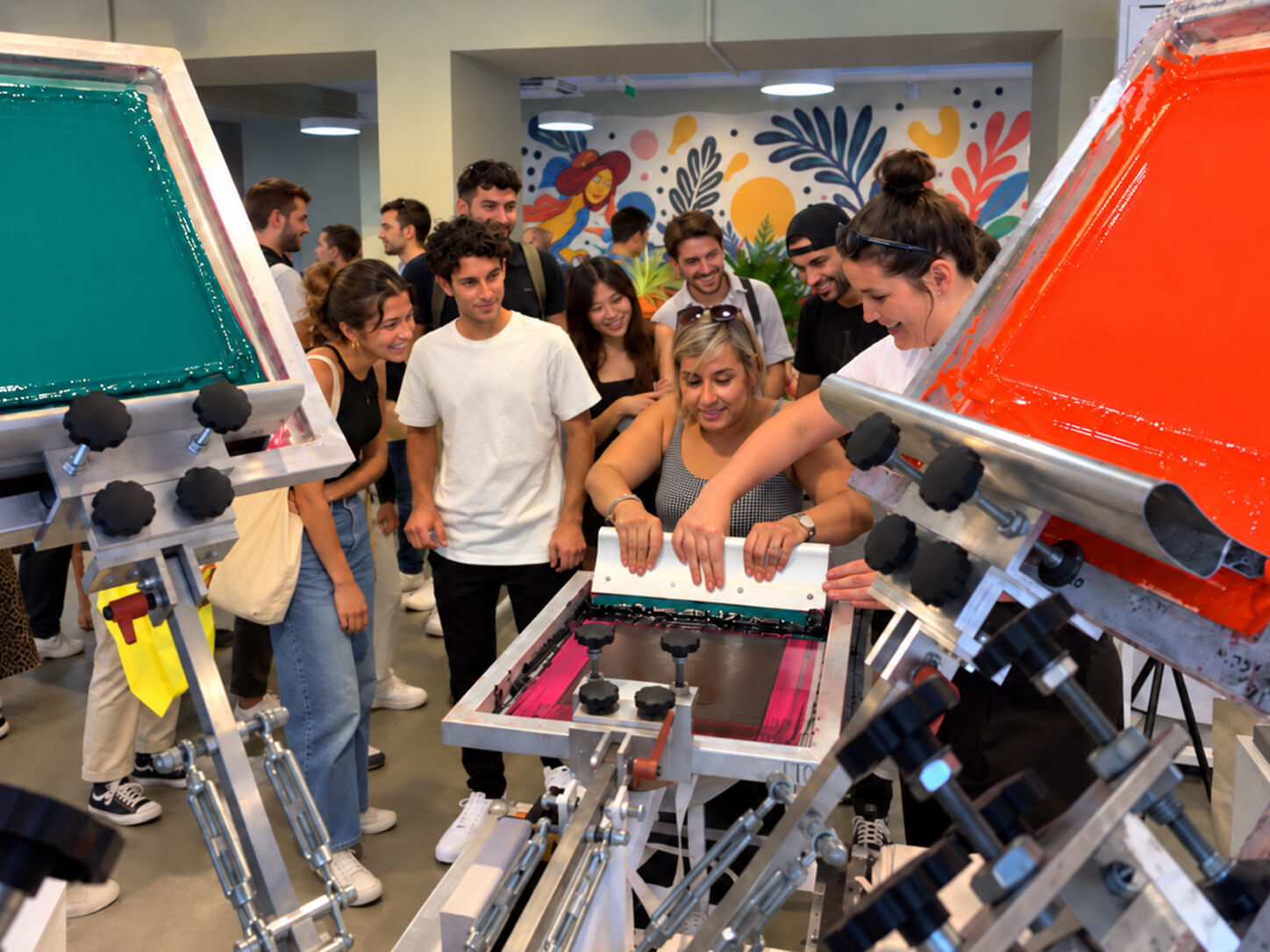 A guest pulls a screen print with help from a Live Ink printer as a crowd watches at a live screen printing event in Milan